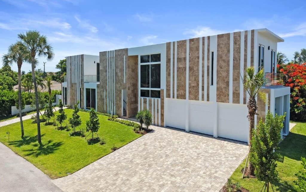 Modern luxury home exterior featuring large-format 24x48 vein-cut travertine veneer panels supplied by Coral Stone USA, installed as an architectural façade accent with clean vertical design lines.